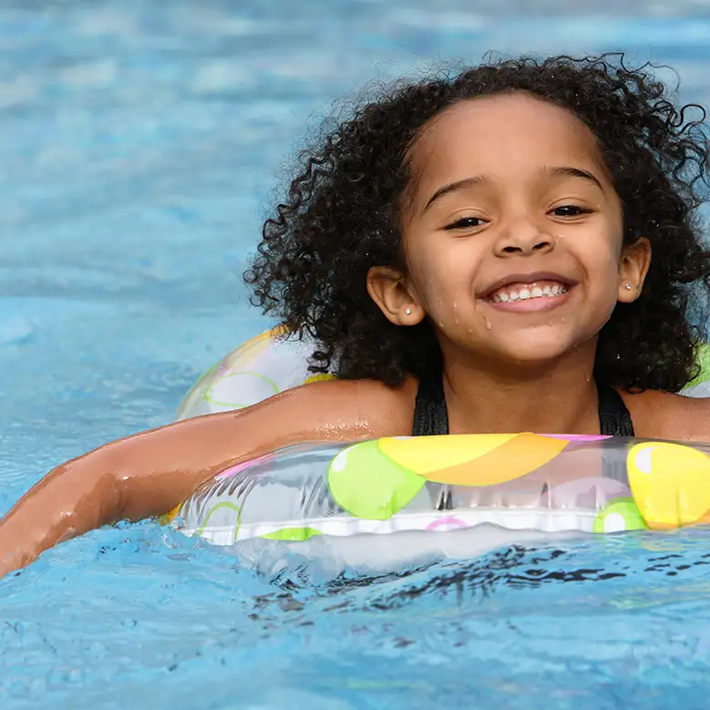 Young African American girl swimming in a pool, using floating inter-tube - Decatur, IL
