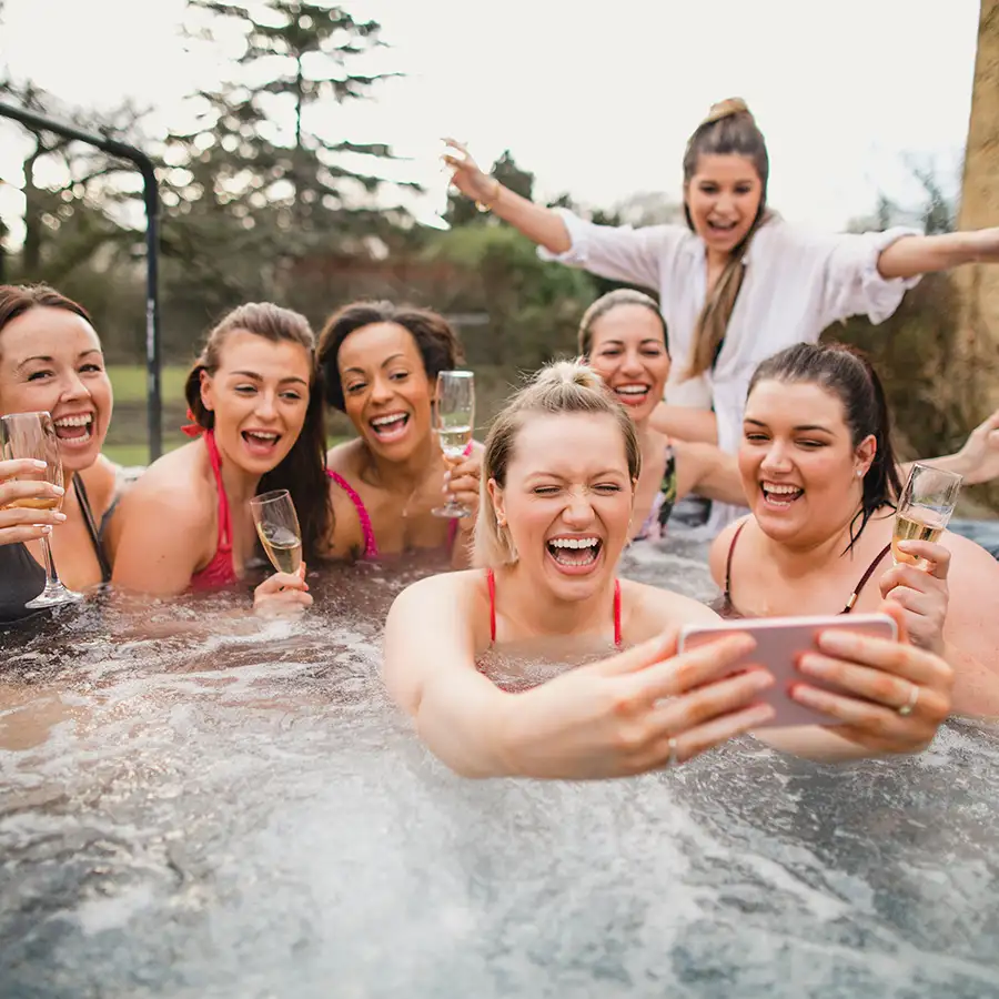 large, diverse ground of female friends celebrating in the hot tub with glasses of champagne - taking a selfie - Decatur, IL