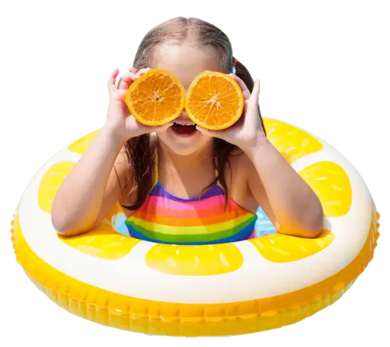 little girl is swimming, wearing a rainbow swimsuit, sitting in a yellow "lemon slice" pool float ring, holding two halves of an orange to her eyes like a bug - goofing around at the pool - Decatur, IL